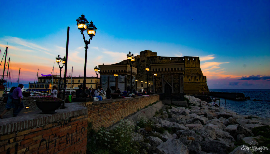 Le Grand Hôtel Vesuvio se détache dans le crépuscule, un palace à l’ancienne, où résonnent les voix des rois, des acteurs et des grands de ce monde qui y ont dormi, depuis 1882. En face, le Castel dell’Ovo, ou château de l’œuf, est un des plus anciens édifices napolitains. Virgile dit avoir enterré un œuf sous ses fondations : tant que l’œuf ne se brisera pas, le château et Naples tiendront debout.